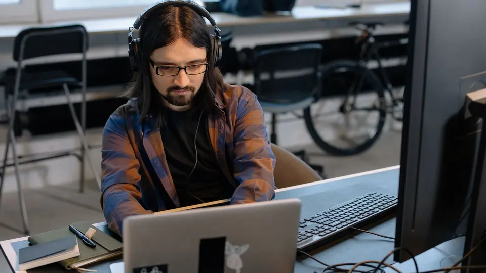 AI engineer smiling while collaborating with automated software on dual monitors