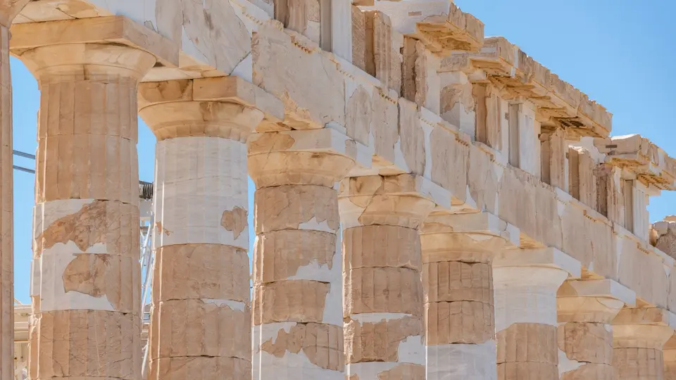 Sunlit ruins of the ancient Roman Forum with towering classical marble pillars