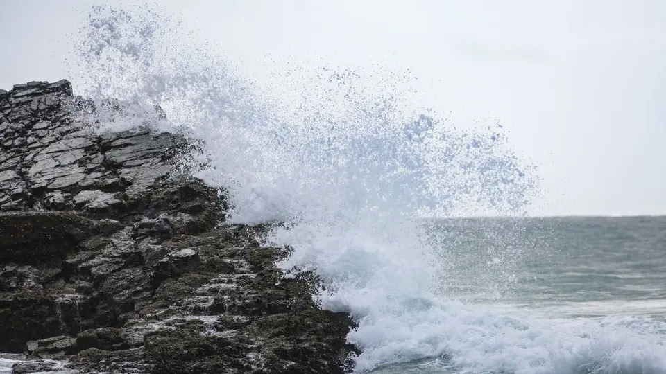 Solitary figure standing calmly on high ocean cliffs during a violent sea storm