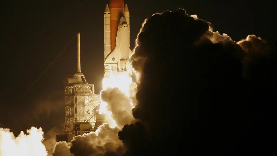 Heavy-lift rocket booster lifting off from launchpad engulfed in billows of fire and smoke
