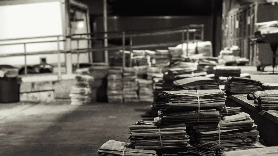 Vintage industrial newspaper printing press idle and gathering dust in warehouse