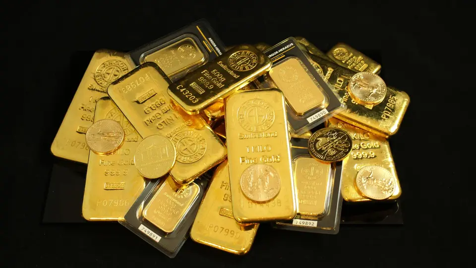 Secure bank vault interior stacked with heavy solid gold bullion bars reflecting warm light