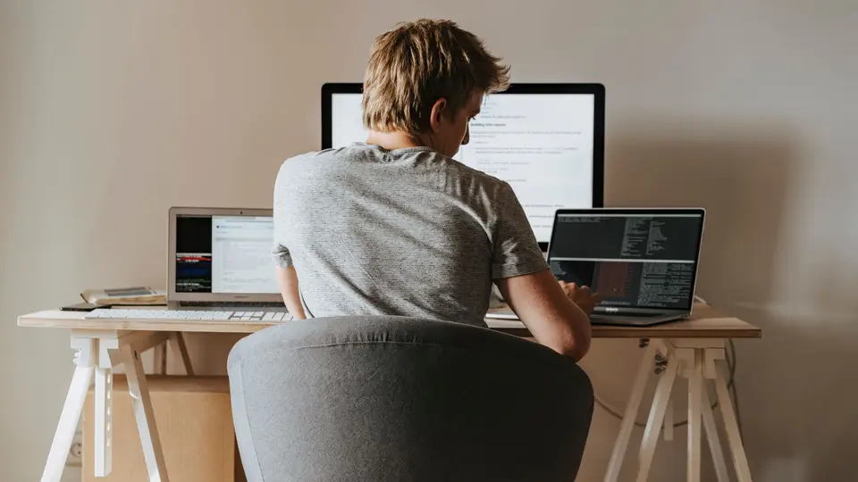 Cybersecurity analyst leaning back in chair staring at resolved puzzle on triple monitors