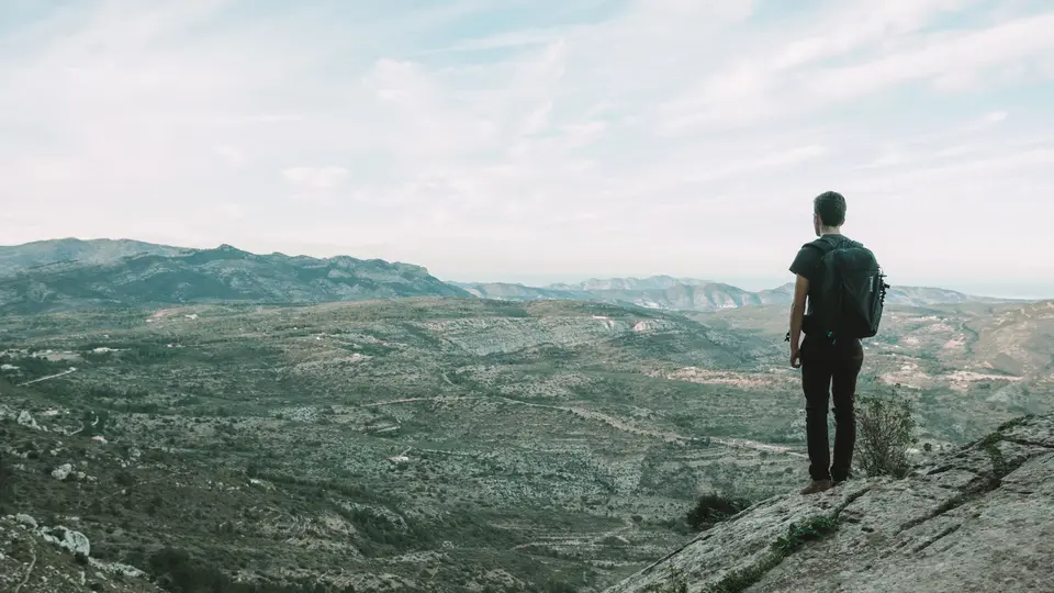 Solo hiker standing on mountain summit breathing fresh air without digital devices