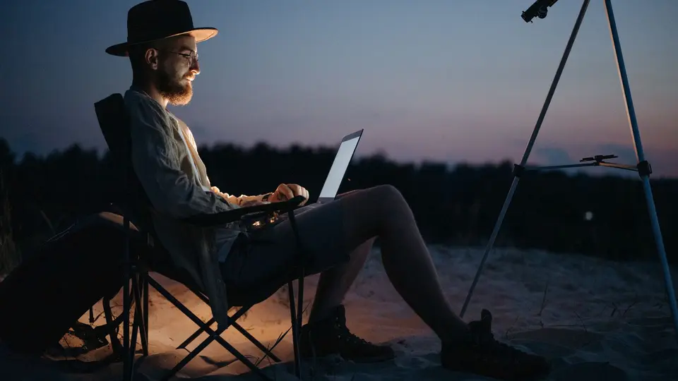 Content remote worker closing laptop at sunset with beach waves in background