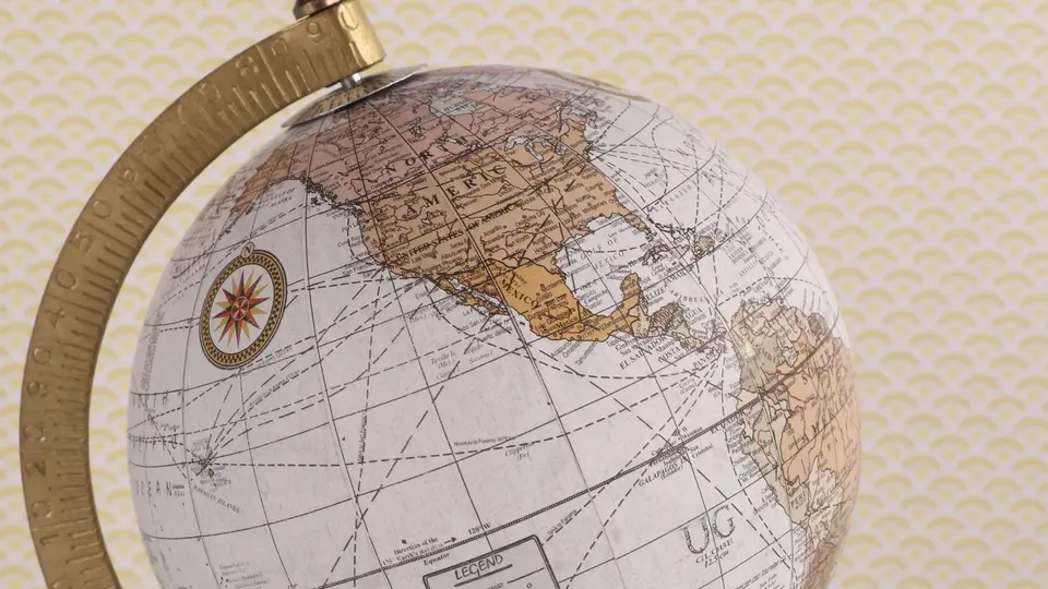 Ancient compass, leather-bound map, and weathered stone artifact on study desk