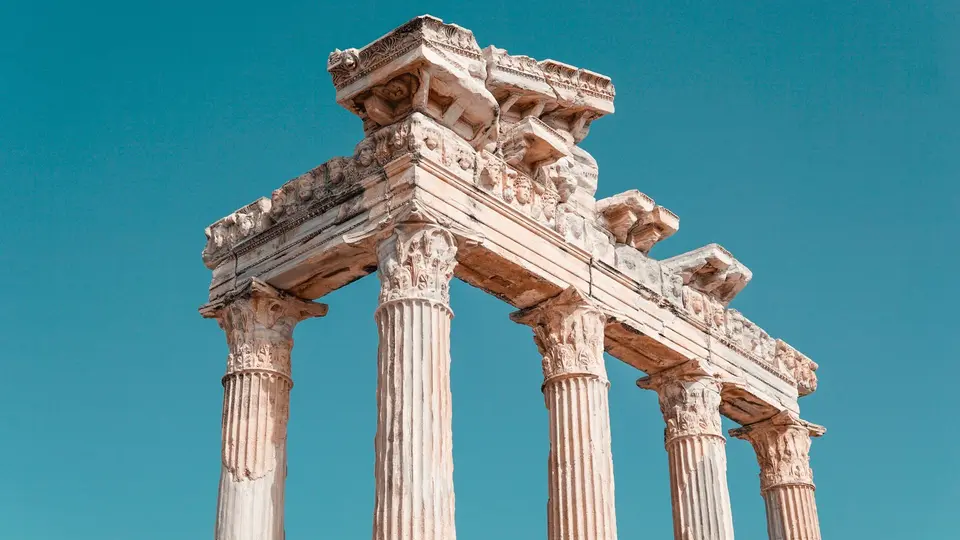 Sunlit ruins of the ancient Roman Forum with towering classical marble pillars