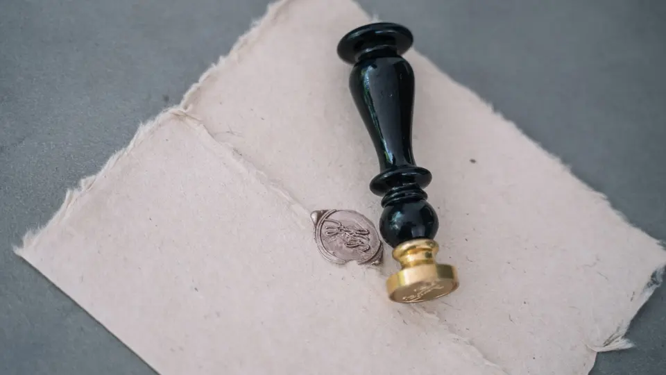 Stone carving of classical motto with candlelight and vintage quill pen