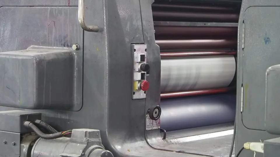 Vintage industrial newspaper printing press idle and gathering dust in warehouse