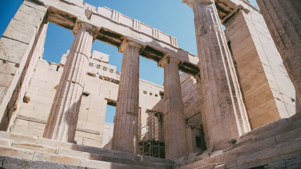 Ancient Greek agora at dawn, painted colonnade in soft focus, silhouettes of gathered figures