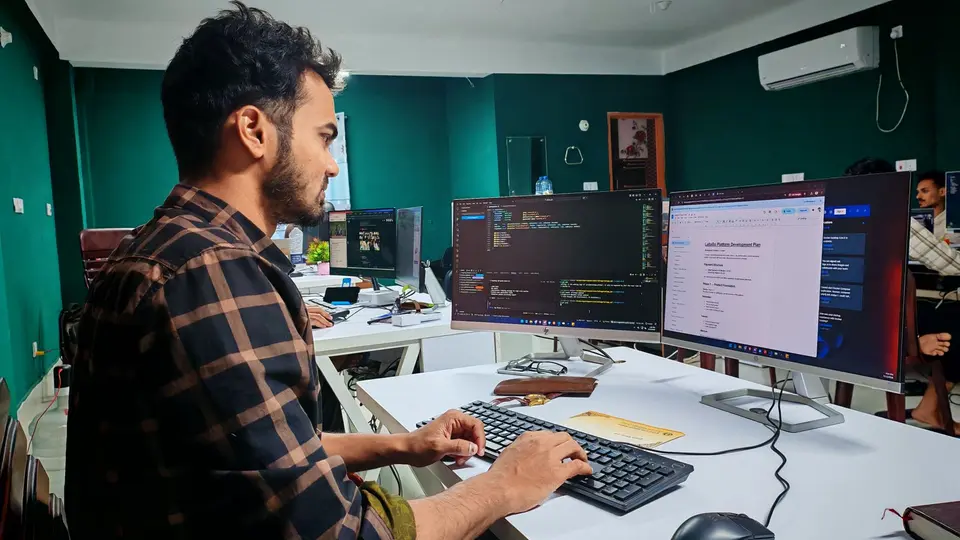 AI engineer smiling while collaborating with automated software on dual monitors