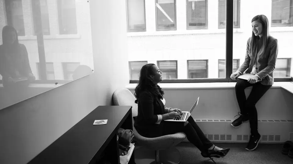 Open-plan startup bullpen with employees working late under exposed industrial pipes