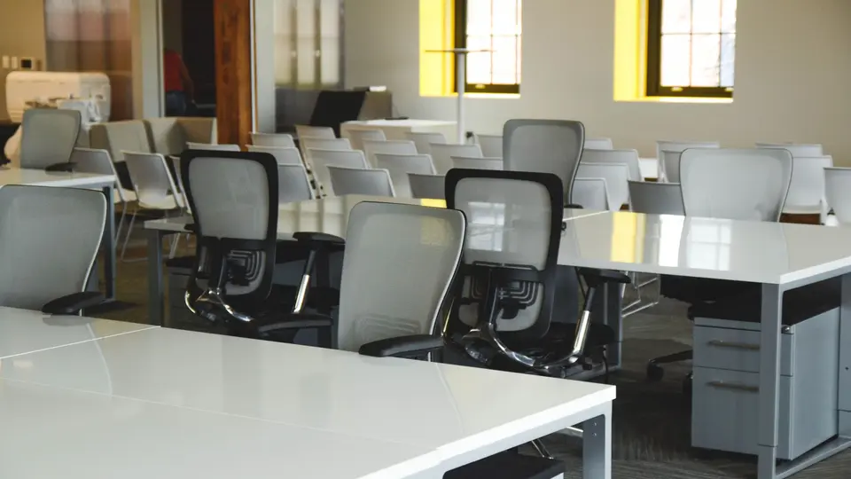 Open-plan startup bullpen with employees working late under exposed industrial pipes